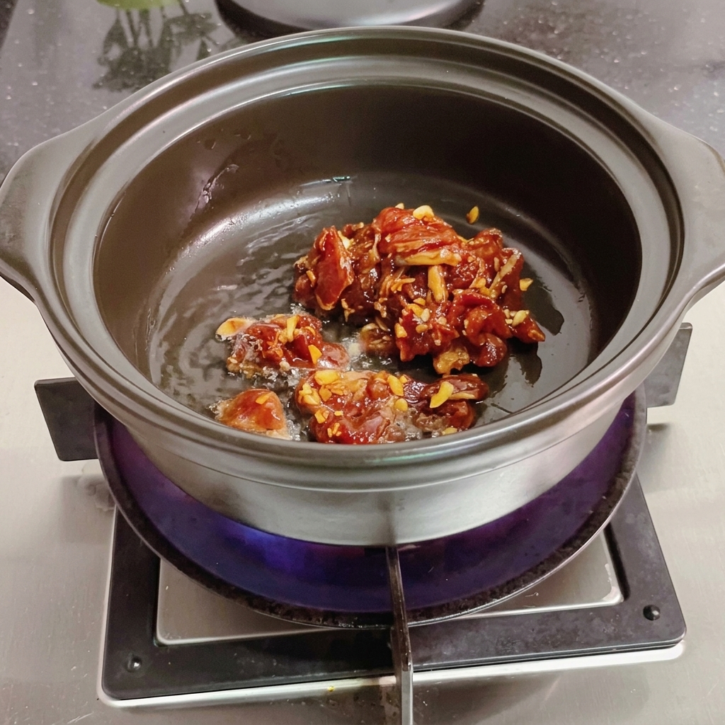 木べらを使って土鍋で肉を炒める様子。
