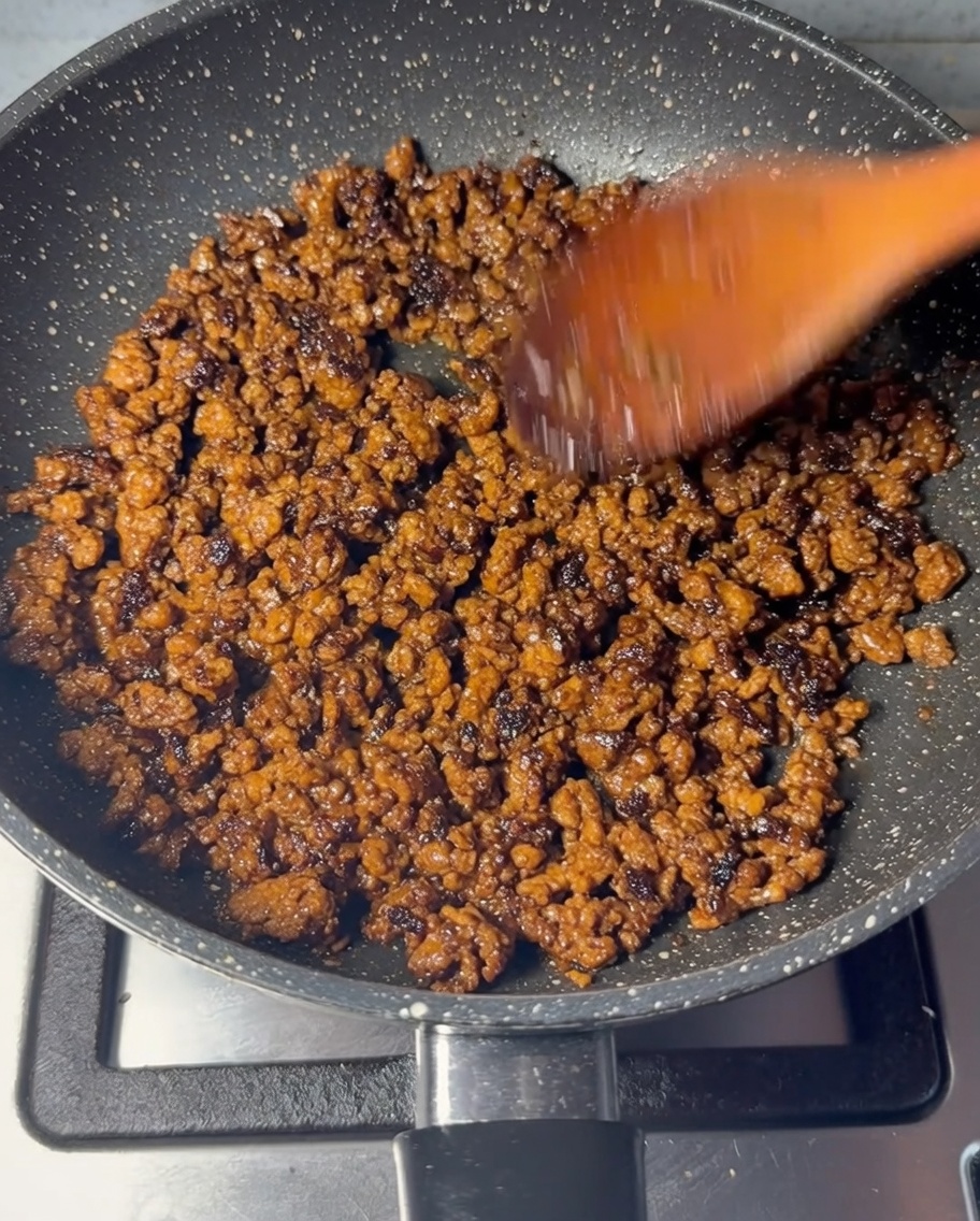 木べらで牛ひき肉を焼き色がつくまで炒めている様子。
