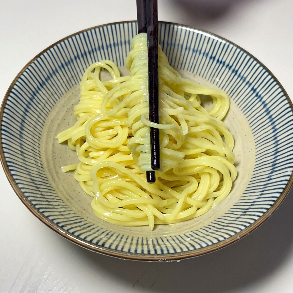 茹で上がった太麺を丼に盛り付けている様子。