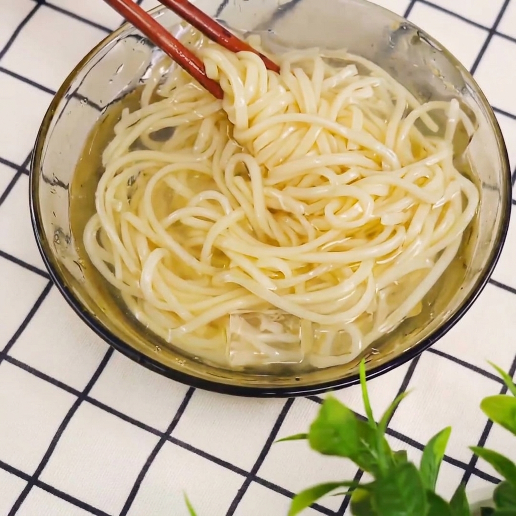 茹で上がった麺を箸で鍋から取り出している様子。
