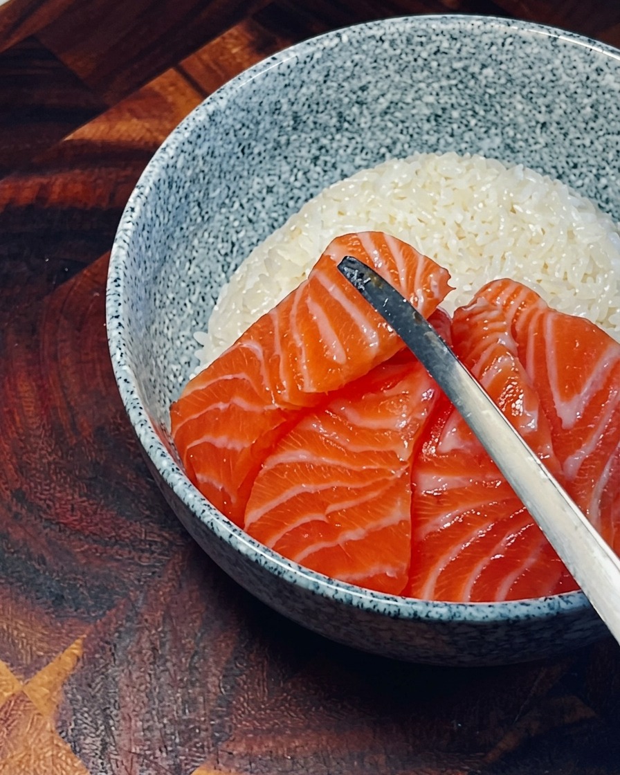 新鮮なサーモンの切り身を、ご飯の上に円状に並べている様子。