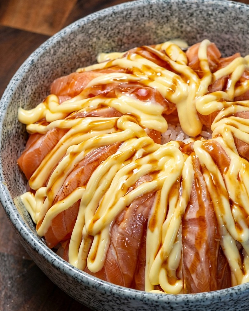 マヨネーズのかかったサーモンに照り焼きソースをかけている様子。