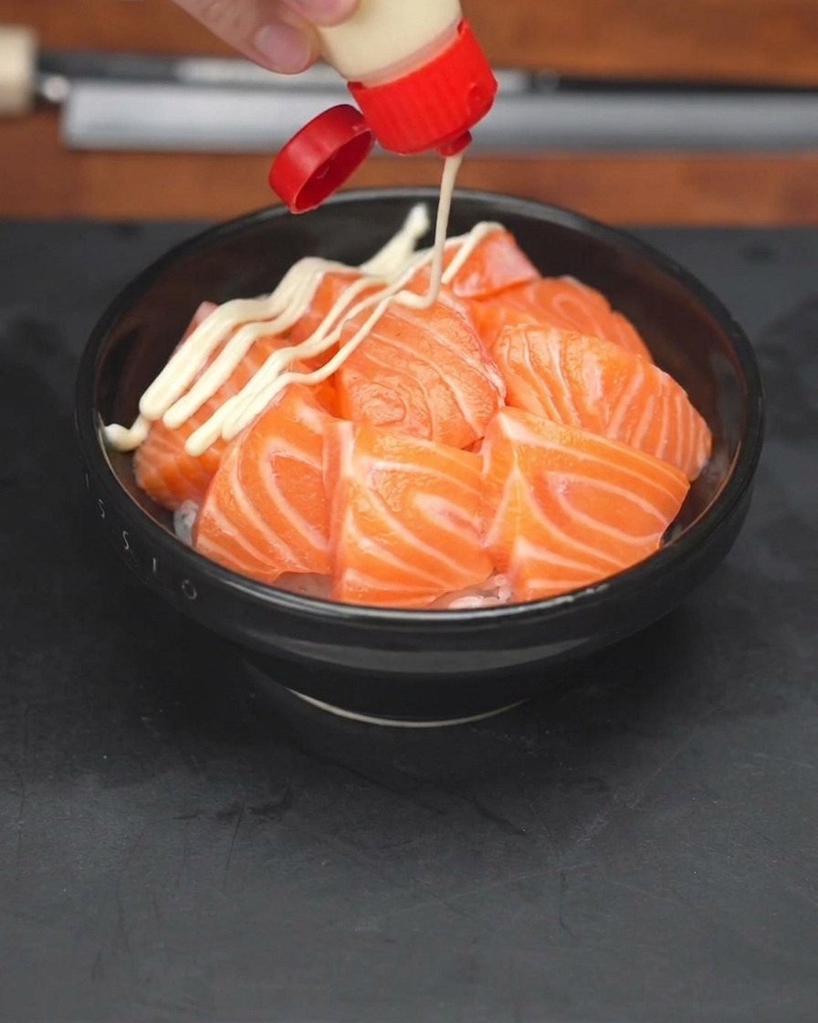 サーモンがのったご飯の上に、マヨネーズをジグザグ模様に絞り出している様子。