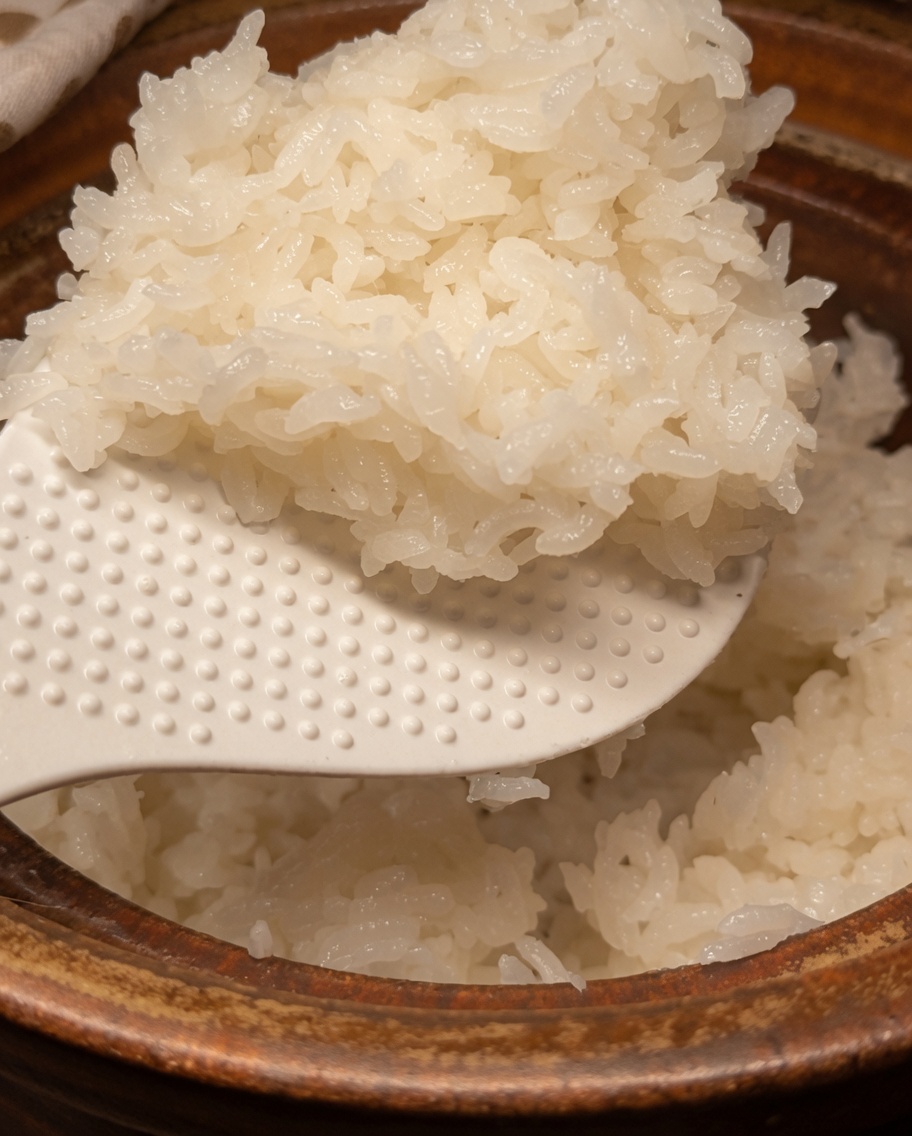 土鍋から移したご飯に、ヘラを使って寿司酢を合わせている様子。