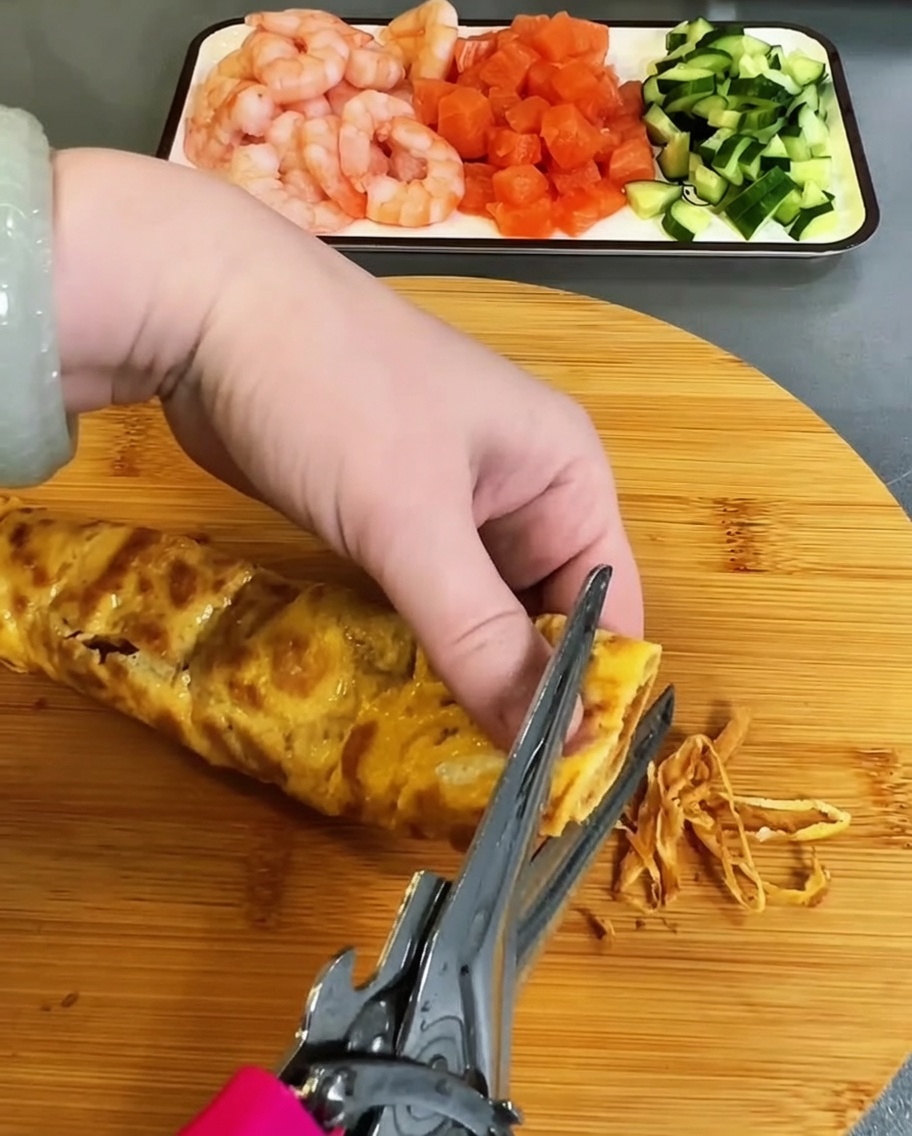 焼き上がった薄焼き卵をキッチンバサミで細長く切っている様子。