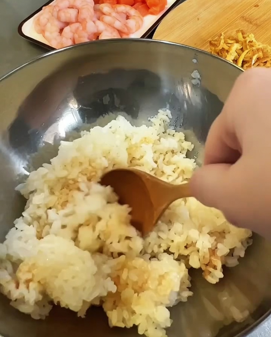 大きなボウルで炊きたてのご飯にすし酢と調味料を合わせている様子。