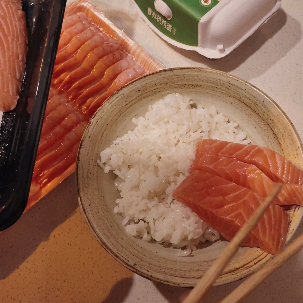 丼の酢飯の上にホタテとサーモンを並べている様子。