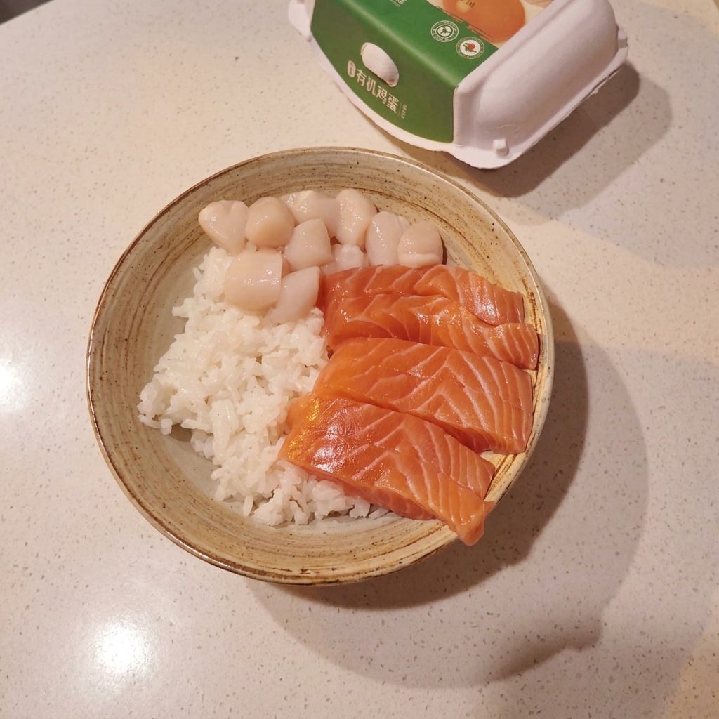 酢飯の上にサーモン、ホタテ、甘エビが綺麗に並べられた丼。
