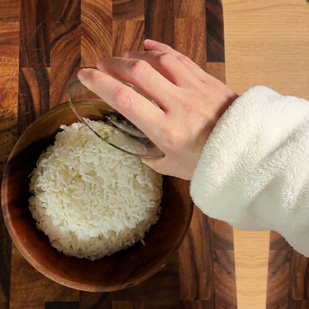 木製のボウルで炊きたてのご飯と寿司酢を合わせる様子。