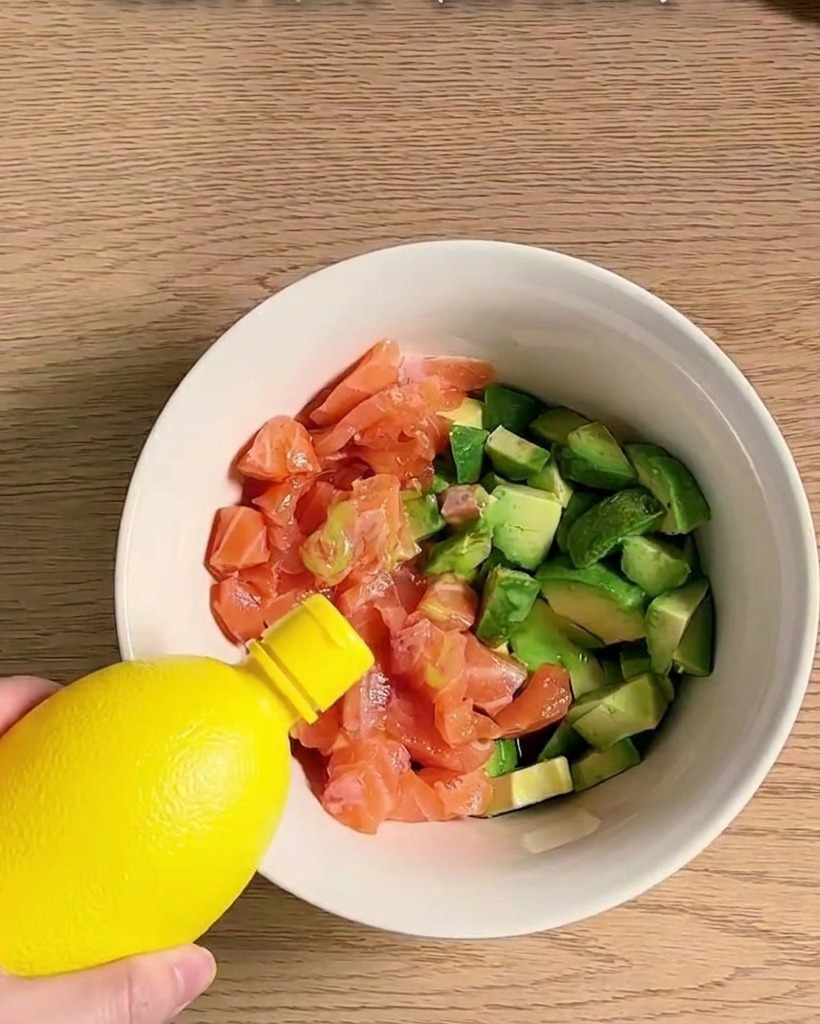 角切りのサーモンとアボカドを、調味料で混ぜ合わせている様子。