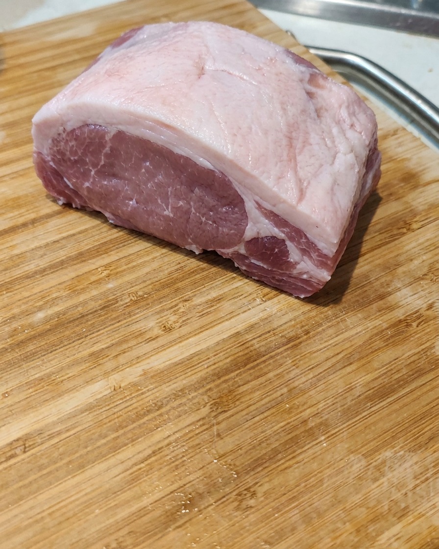まな板の上で豚バラ肉の塊を厚めに切っている様子。