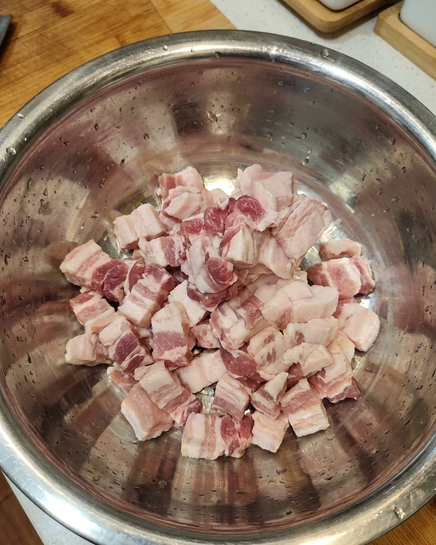 大きめのステンレスボウルに切った豚肉を入れている様子。