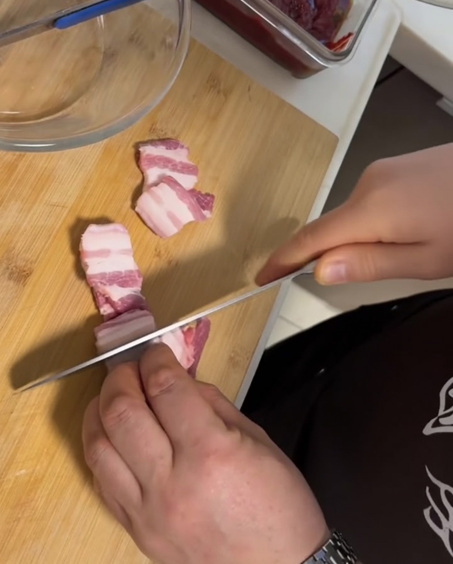 まな板の上に置かれた生の皮付き豚バラ肉と包丁。