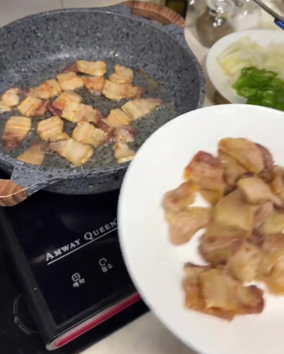 トングを使って焼いた豚バラ肉を白い皿に移している様子。