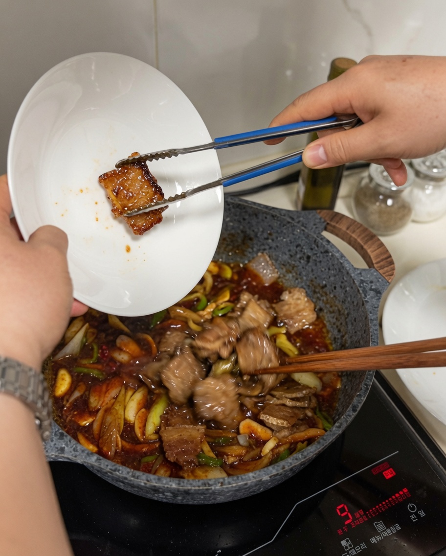 ソースが入ったフライパンに炒めた豚肉を加えている様子。