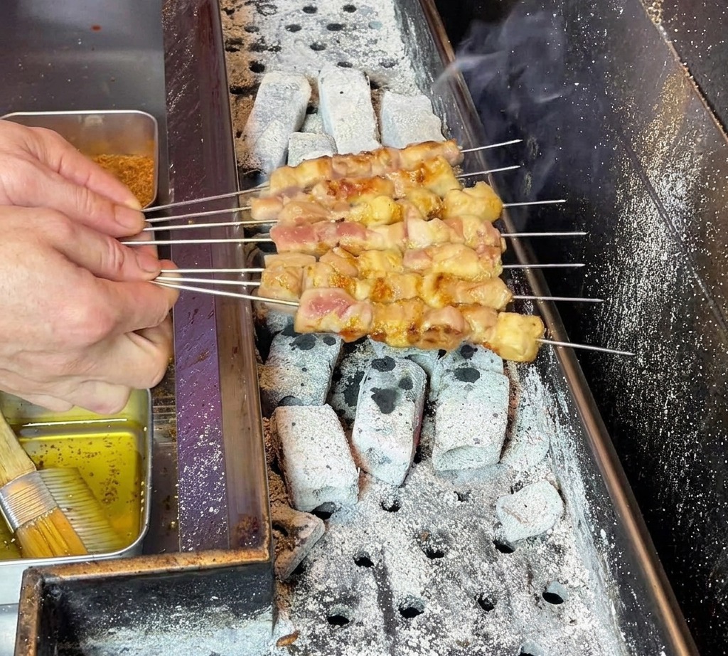 焼きあがった串同士をこすり合わせて脂を全体に広げている様子。