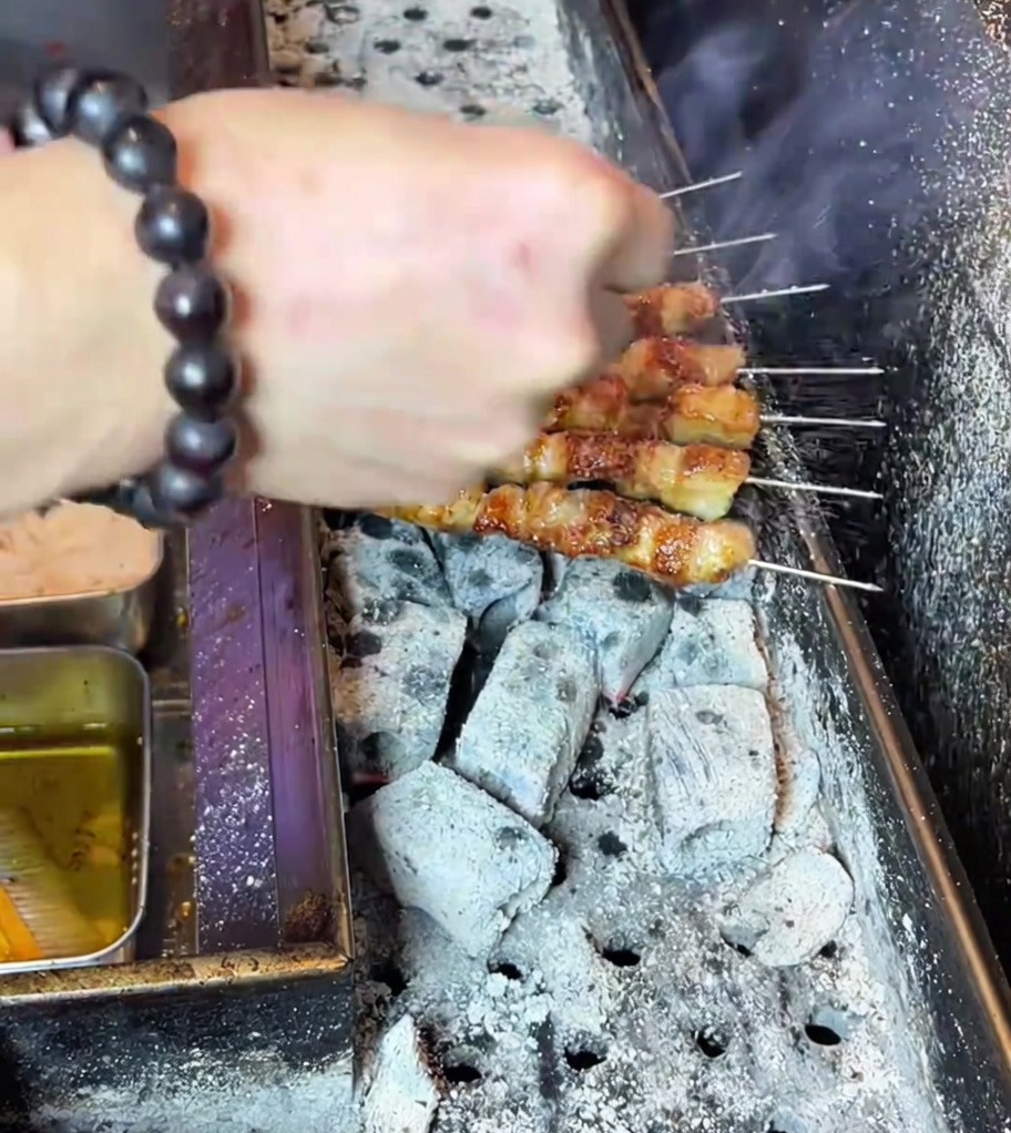 焼き上がった串にスパイスパウダーを振りかけている様子。