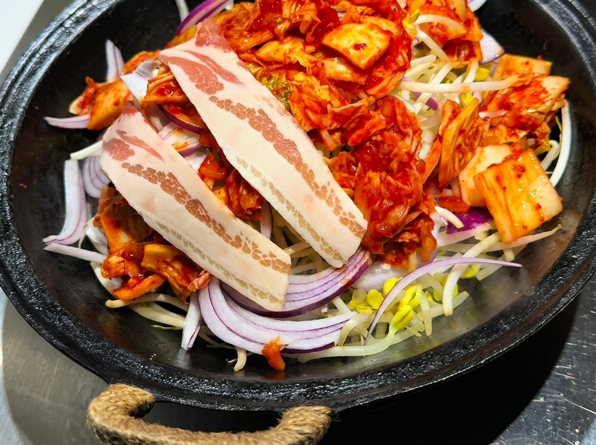 野菜の上に丁寧に並べられた豚バラ肉のスライス。