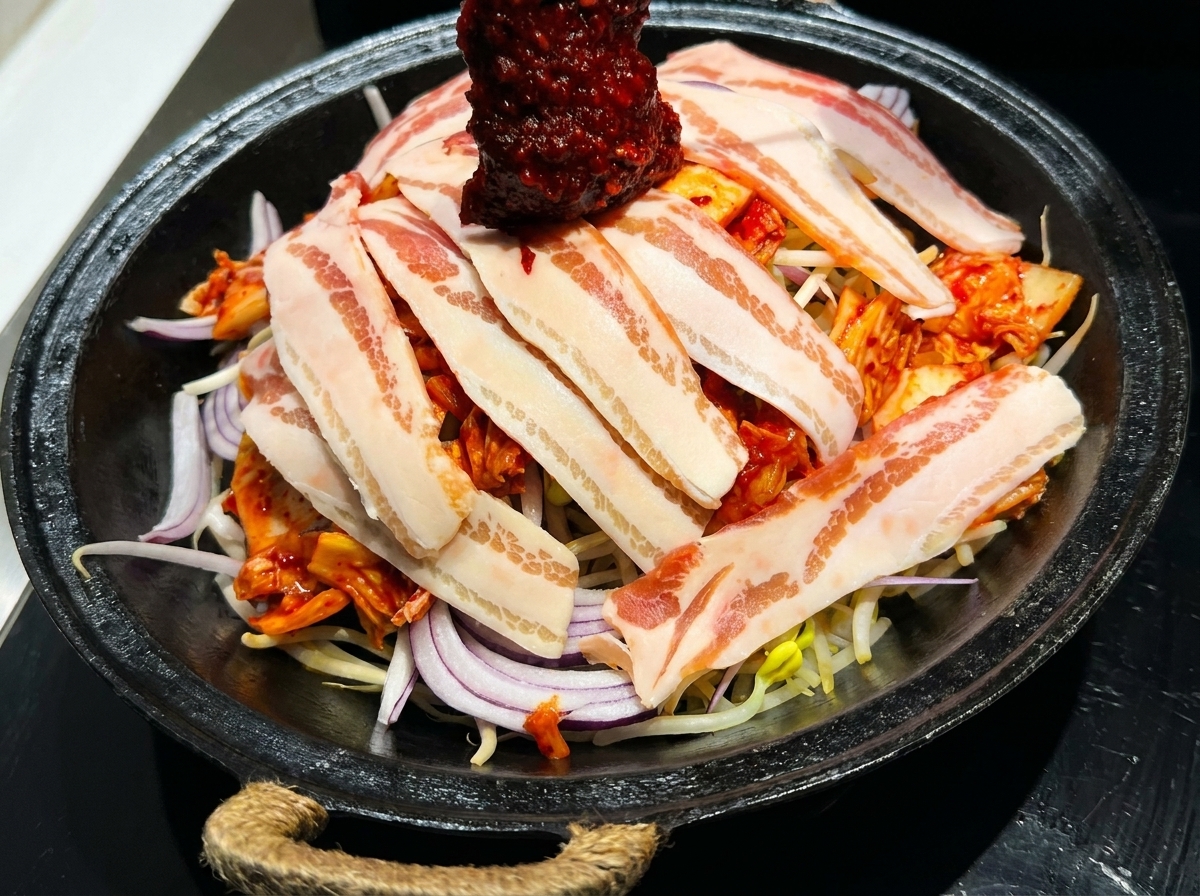 肉と野菜の上に真っ赤なタレを広げている様子。