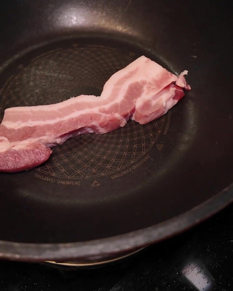 大きな黒い鍋に入れられた厚切りの豚バラ肉。