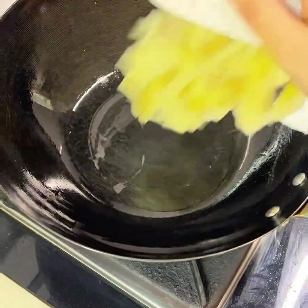 熱した黒い中華鍋に少量の油を入れ、刻んだ高菜を加える様子。