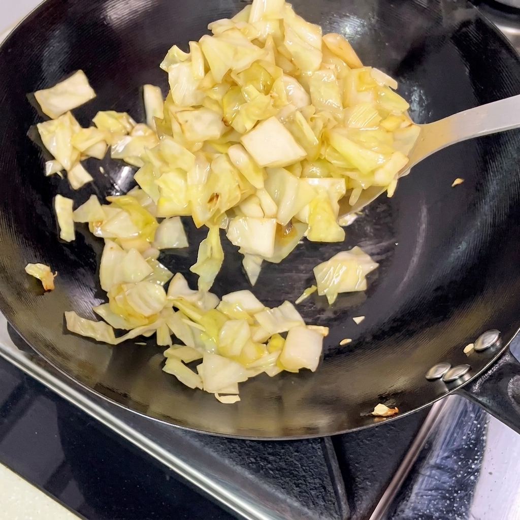 炒めた高菜を中華鍋から皿に移す様子。