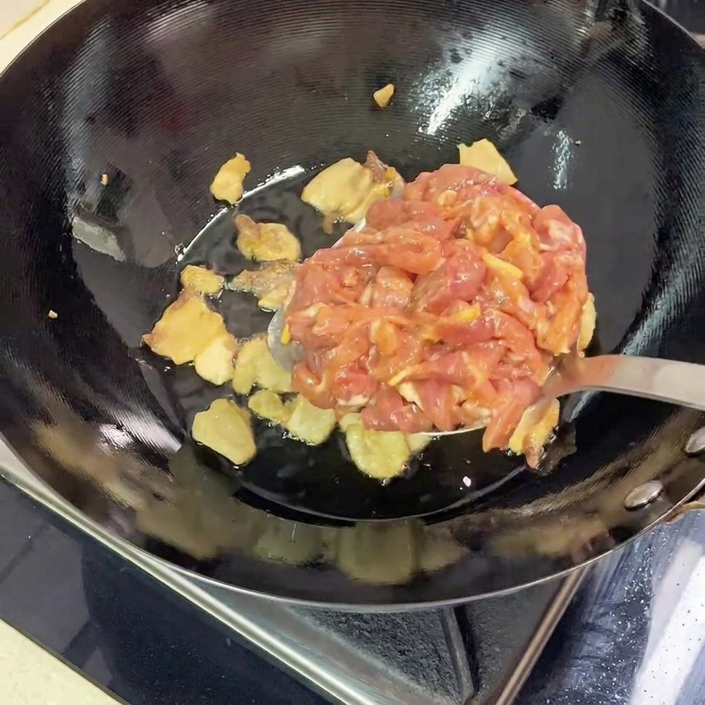 鍋の中の豚バラ肉に、下味をつけた豚赤身肉を加える様子。