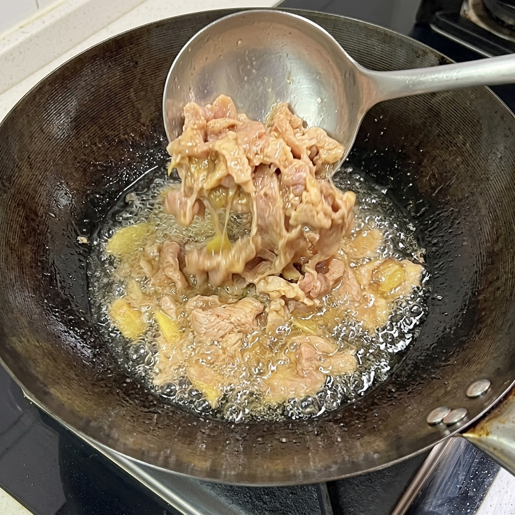 鍋の中で豚肉が焼き色を帯び、火が通っている様子。