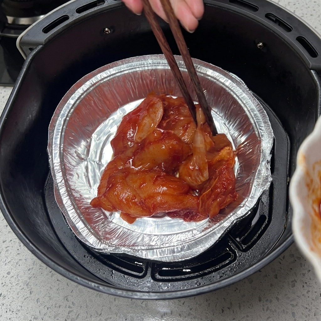 エアフライヤーのバスケットに入れたアルミトレーに、 marinatedチキンを並べている様子。