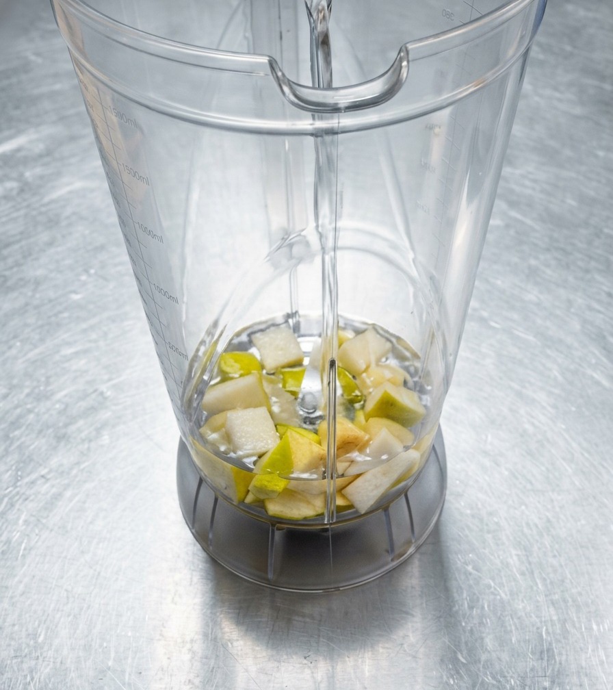 ミキサーに入れた香味野菜に水を少量注いでいる様子。