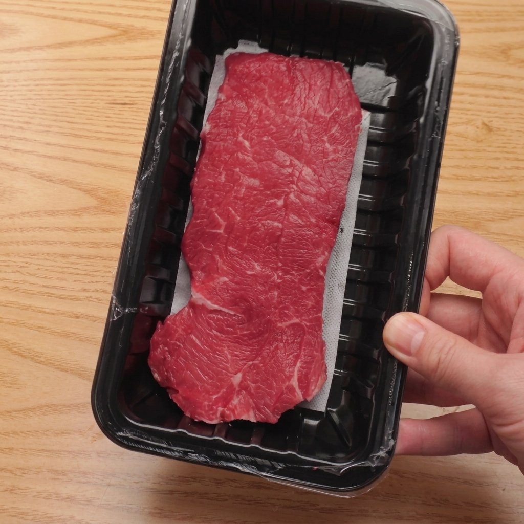 まな板の上で牛ヒレ肉を均一なサイコロ状にカットしている様子。