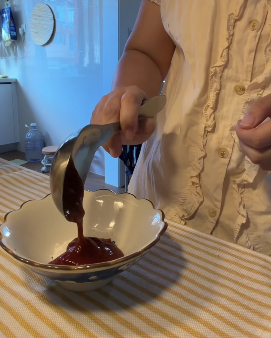 小さな白いボウルで、様々なソースと調味料を混ぜ合わせている様子。