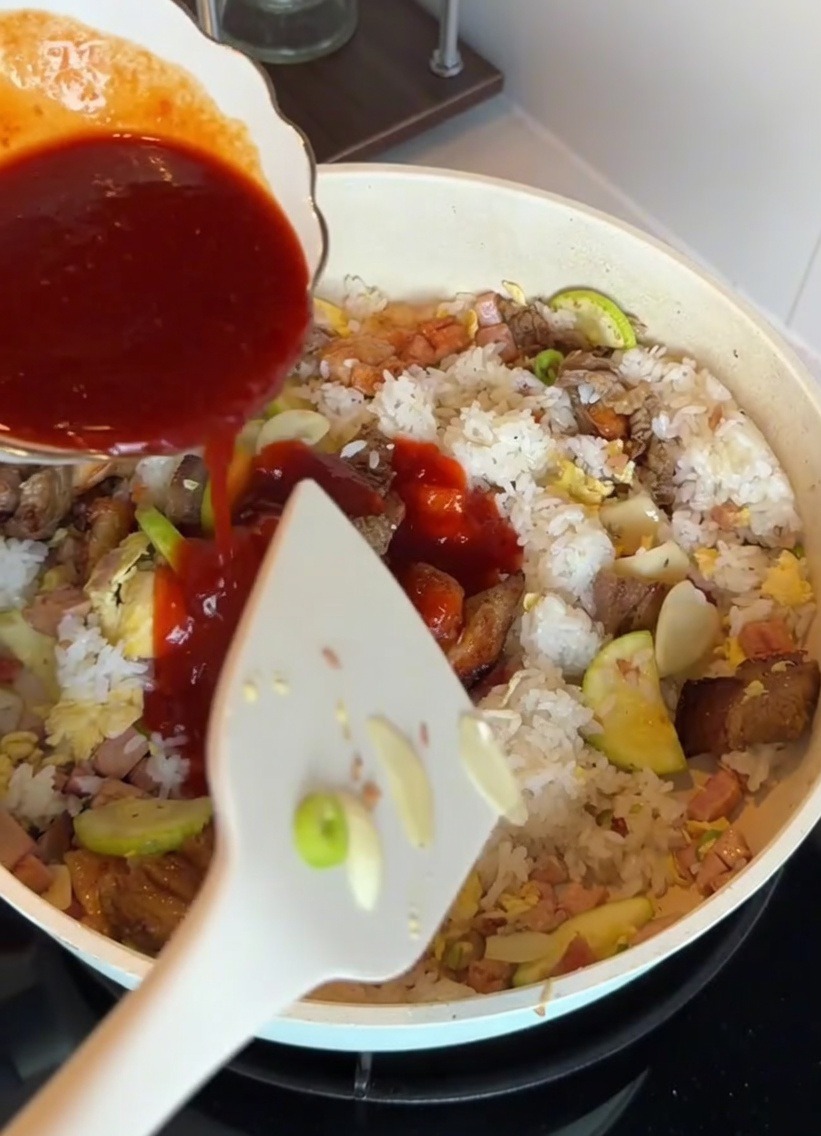 フライパンの中のご飯と具材に、韓国風ビビンバソースをかけている様子。