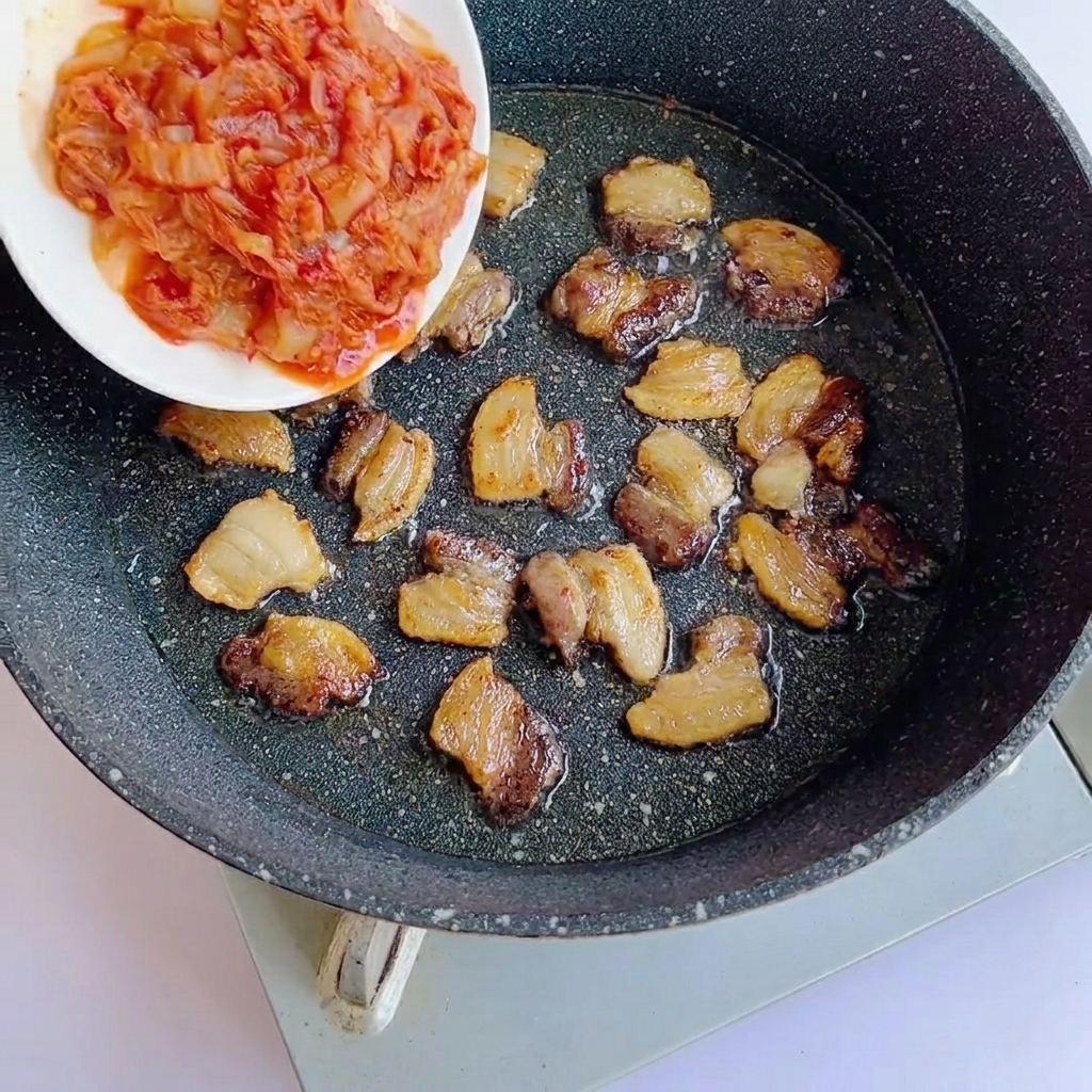 豚肉にキムチとソースを加えている様子。