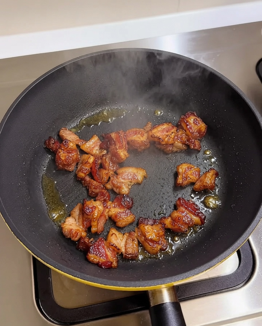 熱したフライパンでこんがりと焼かれる豚バラ肉。