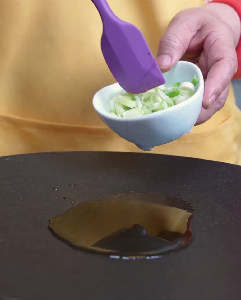 フライパンでごま油と青ねぎを炒めている様子。