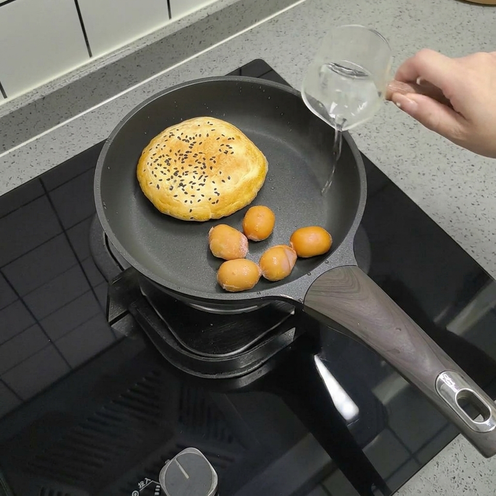 フライパンに入ったソーセージに少量の水を加える様子