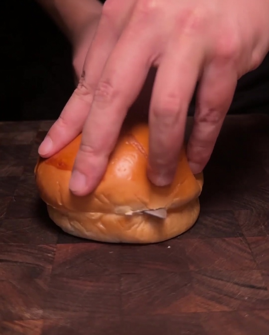 フライパンに溶かしたバターの中で、2つにスライスしたバーガーバンズをきつね色になるまで焼いている様子。