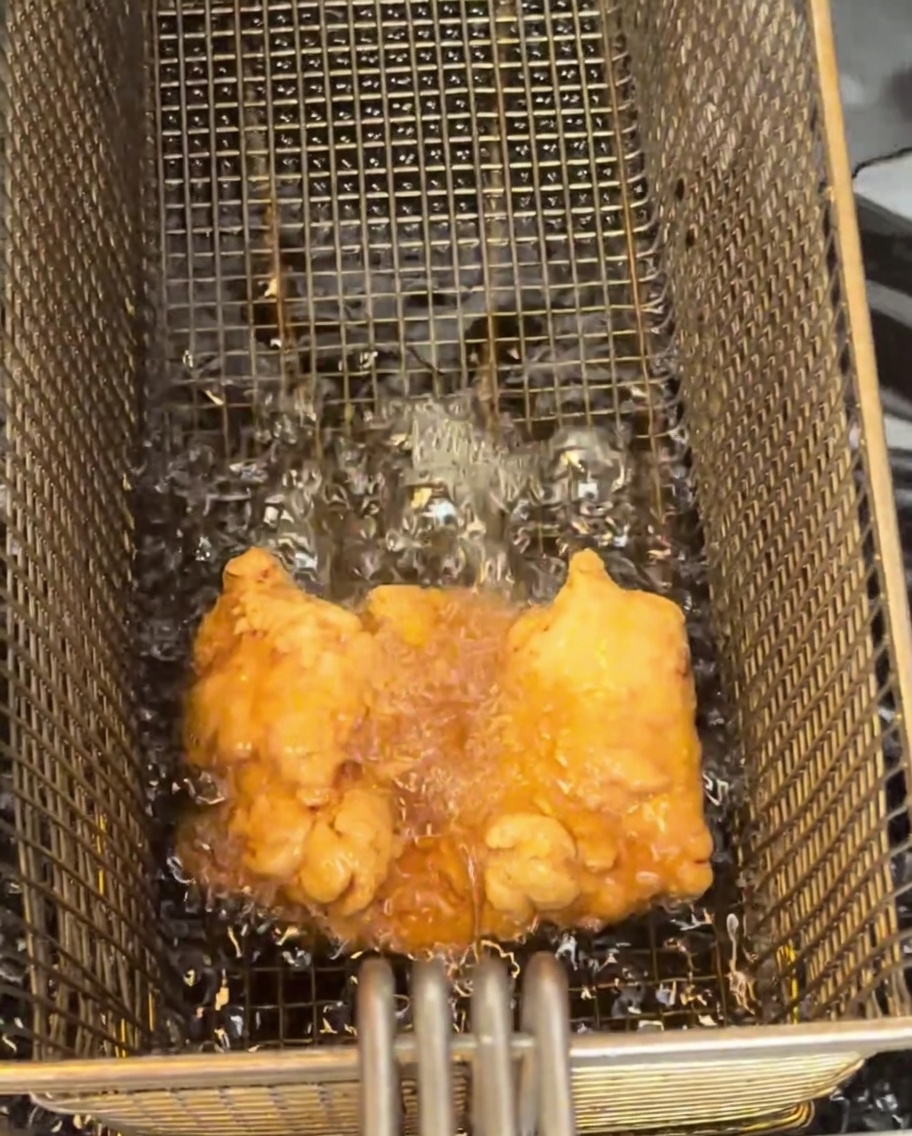 揚げたての鶏もも肉を網に載せている様子