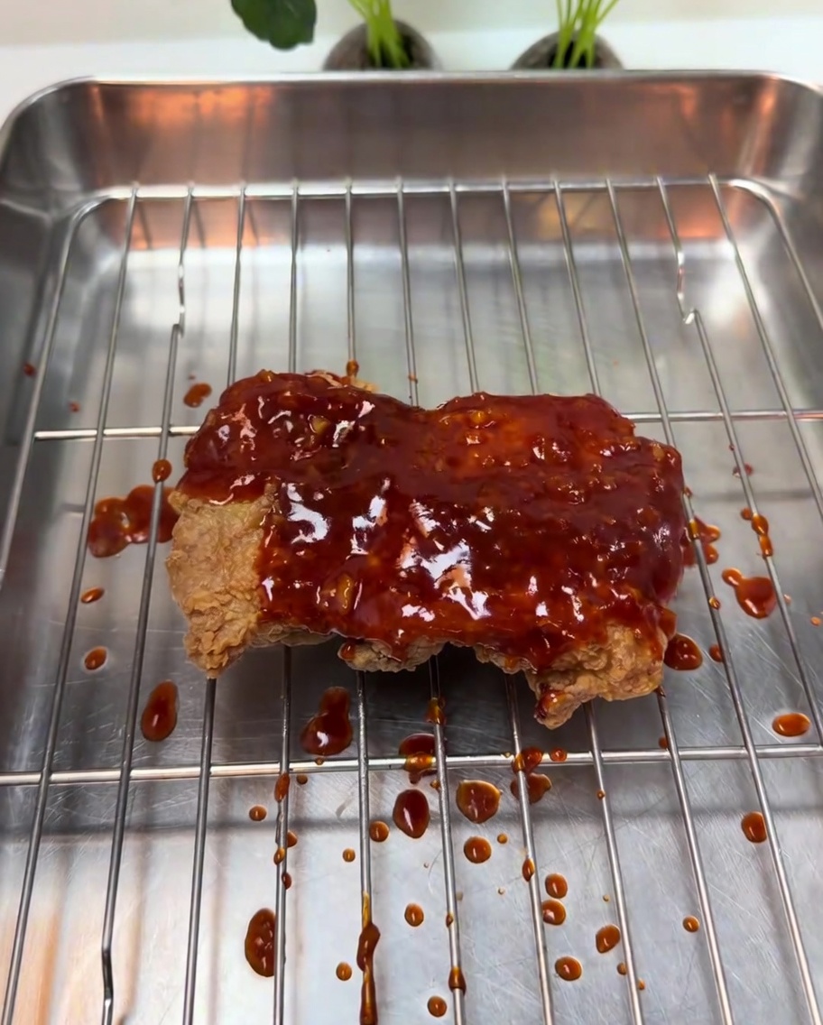 フライドチキンに甘辛いタレを絡めている様子