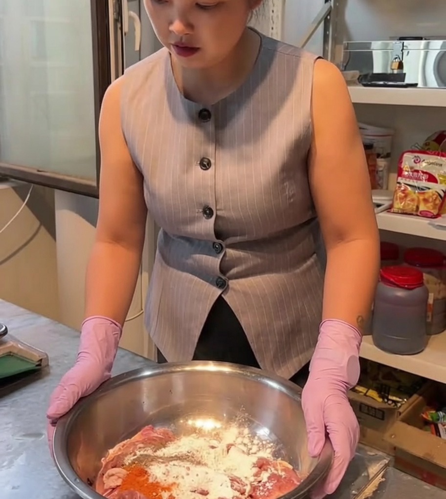 大きめのステンレス製ボウルで、鶏肉とスパイスを混ぜ合わせている様子。