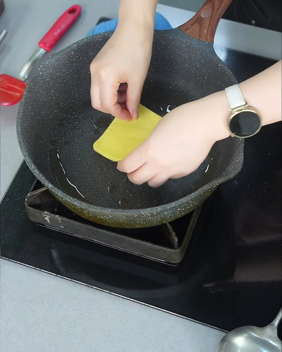 フライパンの中で、こんがり焼けたビーフパティの上にのせられたスライスチーズが溶け始めている様子。