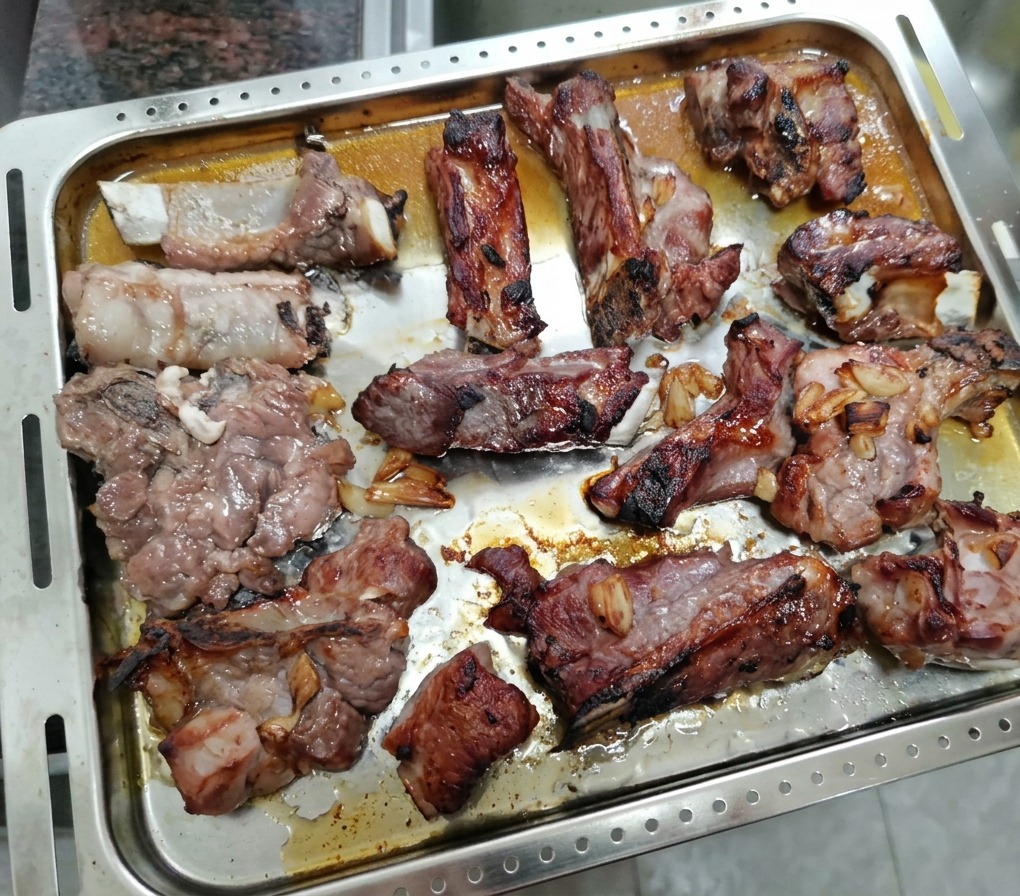 焼き途中のスペアリブをトレイから取り出し、蜂蜜を塗っている様子。