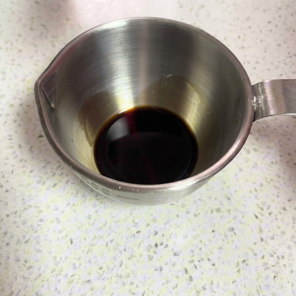 ステンレス製の計量カップにたまり醤油を注いでいる様子。
