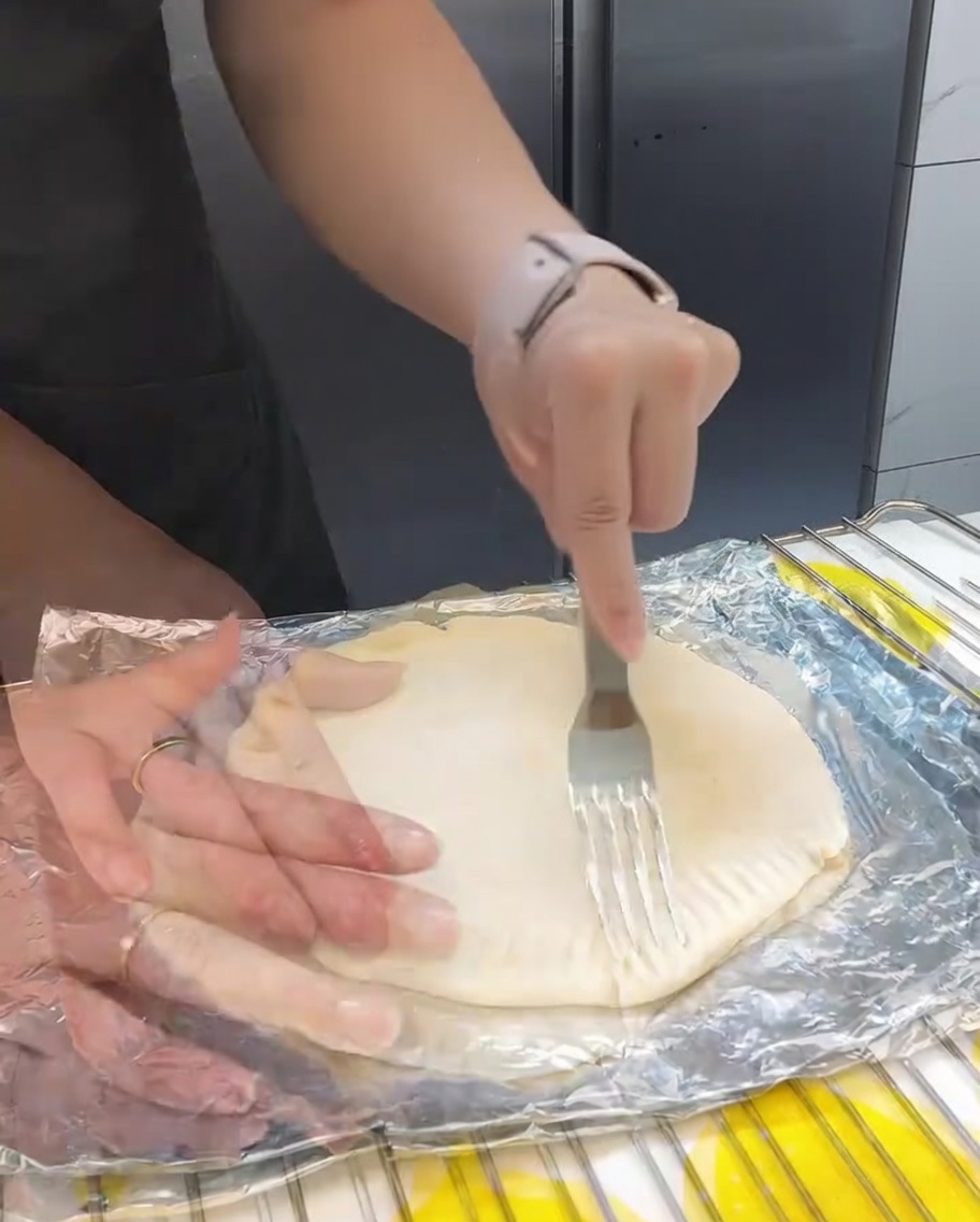 フォークを使ってネギ焼きの縁を押し付け、形を整えている様子。