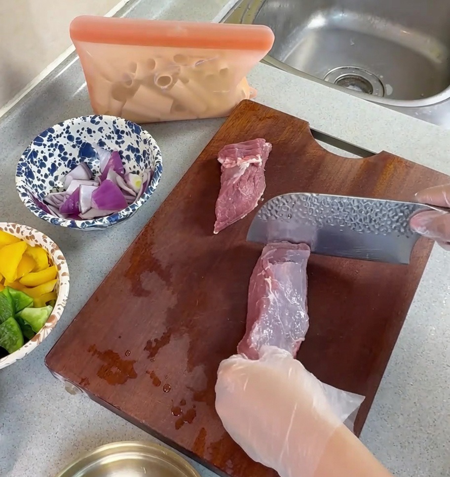 まな板の上で豚バラ肉を薄切りにしている様子。
