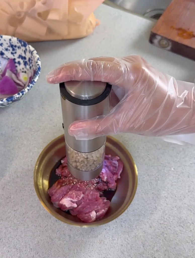 ボウルに入った豚肉に醤油や胡椒をかけて下味をつけている様子。
