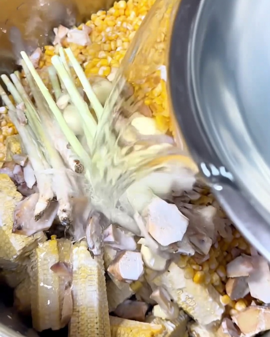 水が入ったボウルから、鍋の中の食材が浸かるまで水を注いでいる様子。