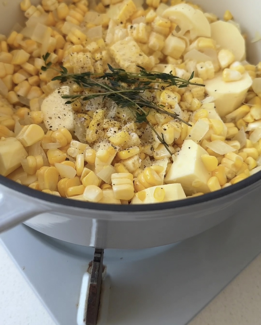 野菜とタイムの枝が入った鍋に、澄んだ水を注いでいる様子。