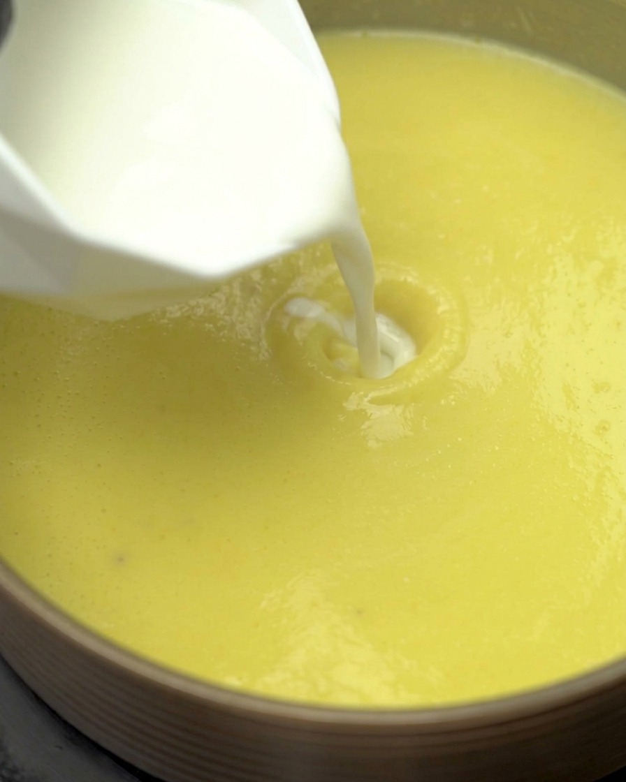 鍋に牛乳と生クリームを注いでいる様子。